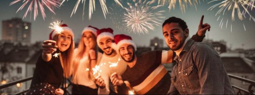 Family celebrating New Year’s Eve in Miami with sparklers and fireworks in the background.