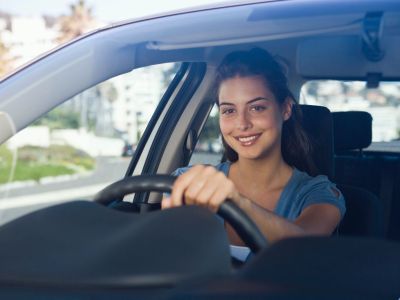 young woman smiling while driving a car insured by American US Insurance in Homestead Florida
