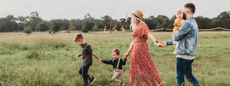 family holding hands while walking on a field