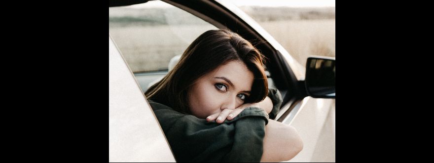 Young woman leaning out of car window.