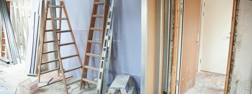 Unfinished interior renovation with exposed ceiling wiring, concrete floors, and newly framed doorways.