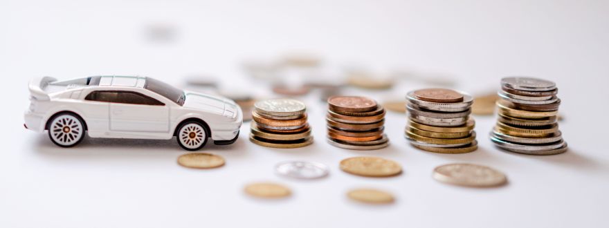 A picture of a toy car sitting next stacks of coins.