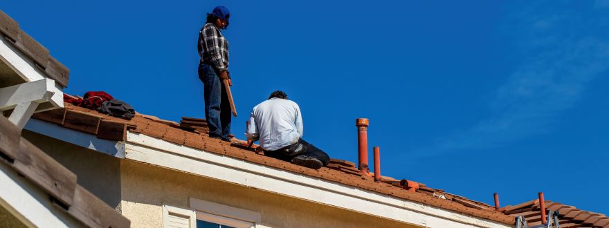Photo of construction workers appearing to repair a tile roof.