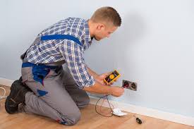 Man on his knees working on a power outlet.