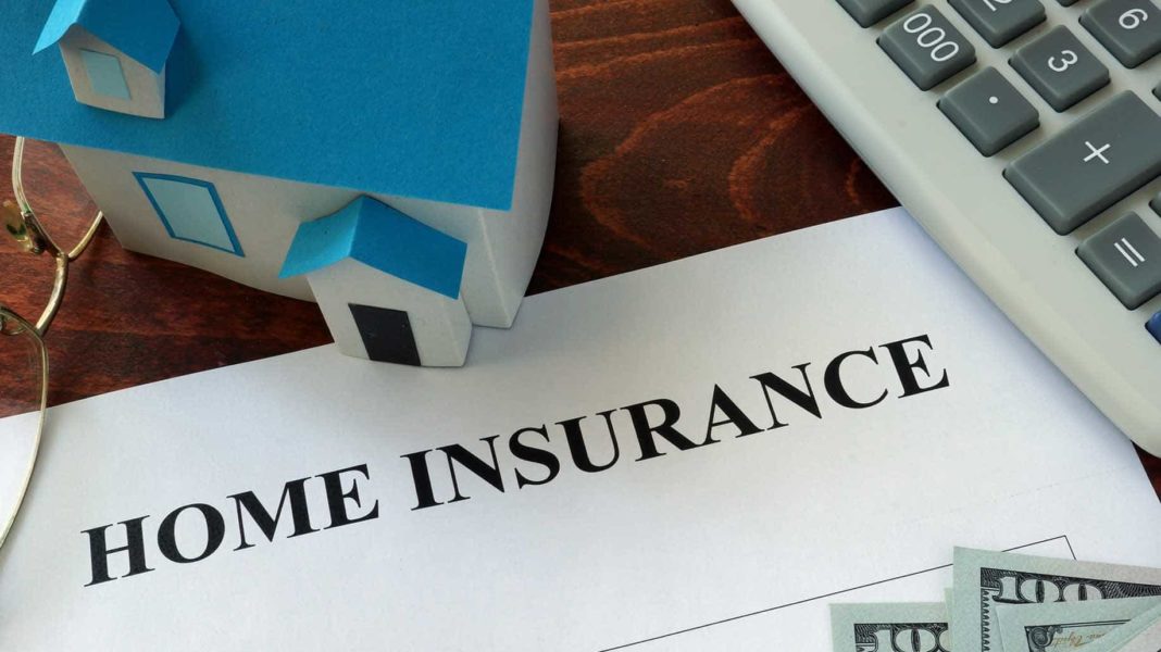 Model of a home sitting on a desk next to a page that says "home insurance". 