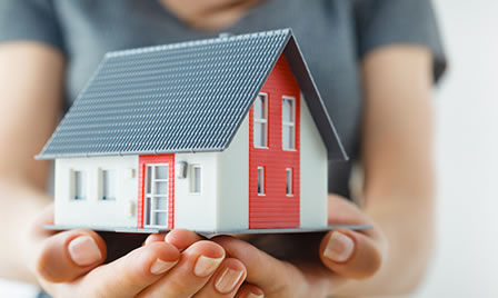 Hands holding a model of a house.