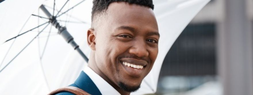 Well-dressed man smiling at the camera, holding a white umbrella.
