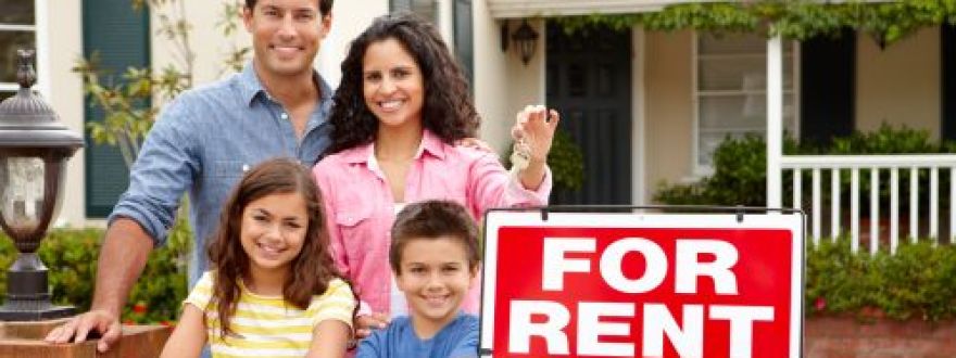 Happy family of four standing outside a house with a