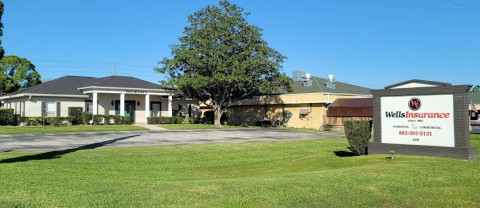 Image of an Insurance office, with a sign on green lawn that says